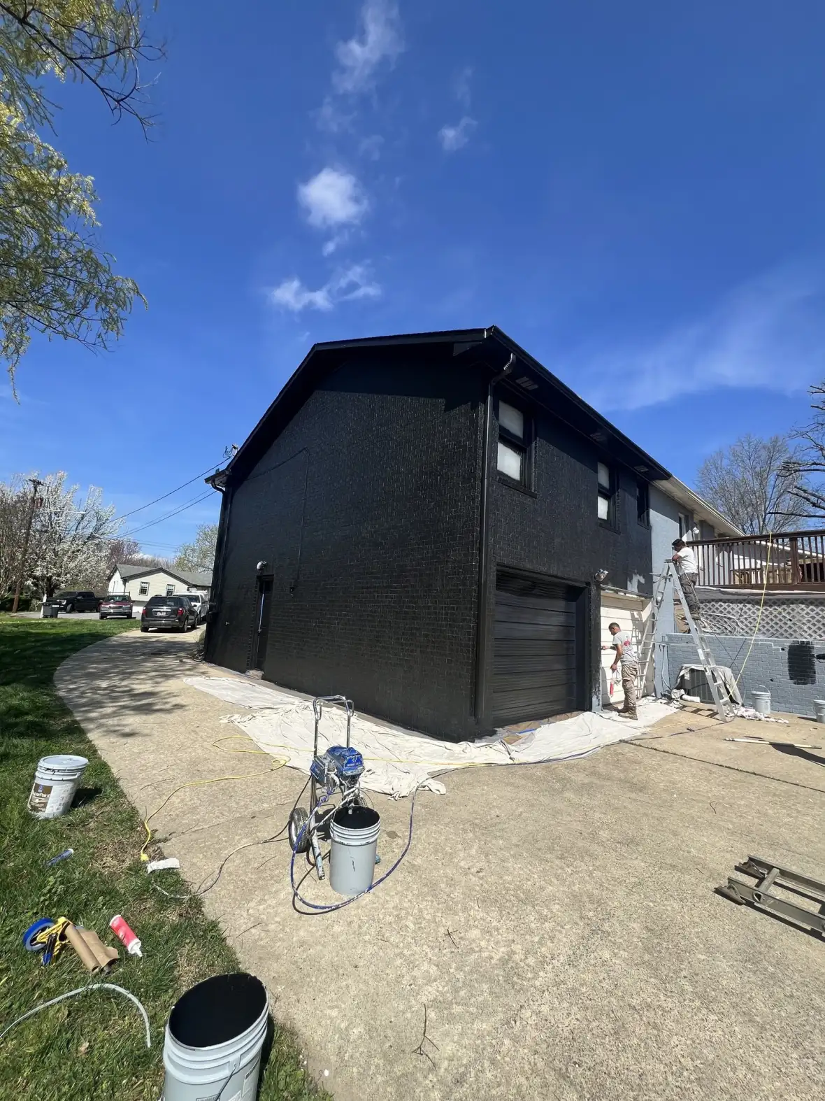 Exterior residential repaint — bold black brick home by Drop Zone Painting